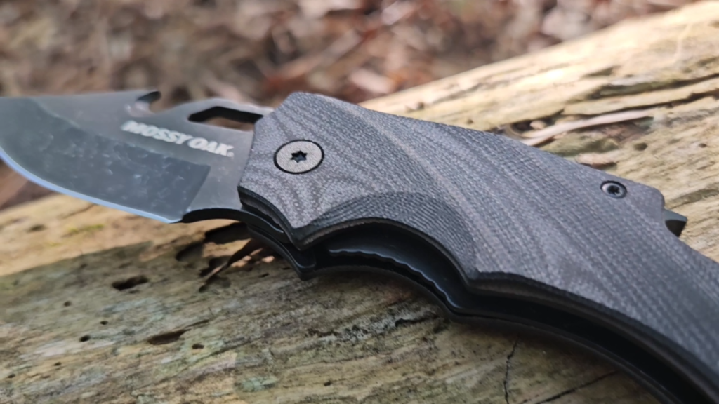 Close-up of John’s Mossy Oak mini pocket knife resting open on wood
